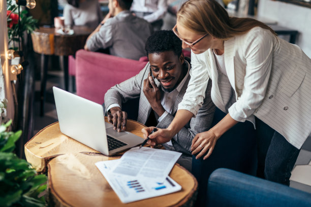 一位女士拿着一些文件走到一位同事面前，准备进行一次非正式的讨论图片下载
