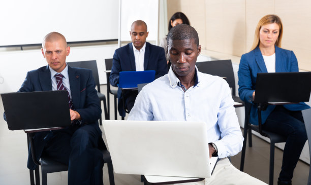 一群跨国人士在商务研讨会上使用笔记本电脑工作图片下载