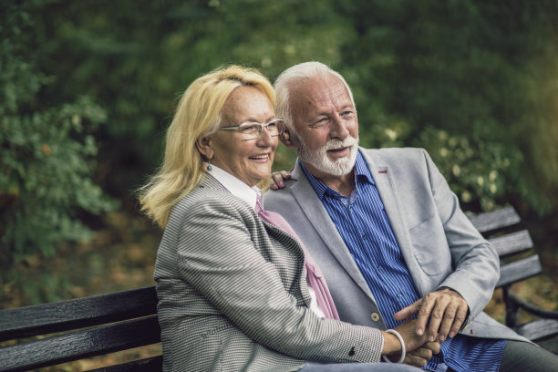 一对听力有问题的老年夫妇坐在户外的长凳上图片下载