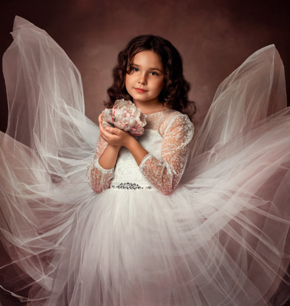 一个十岁的女孩穿着白色的连衣裙，站在牡丹花旁。这个女孩有一头棕色的卷发。她穿着新娘的礼服。
女孩手里拿着一朵牡丹图片下载