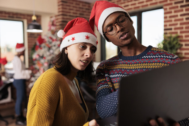不同的同事在节日的办公室里看着笔记本电脑图片下载