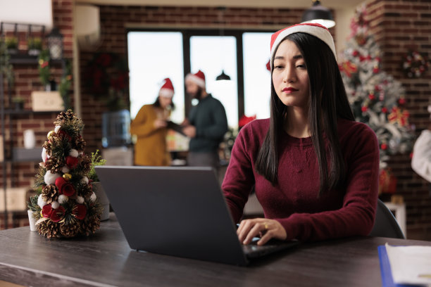 带圣诞老人帽子的女职员在办公室工作图片下载