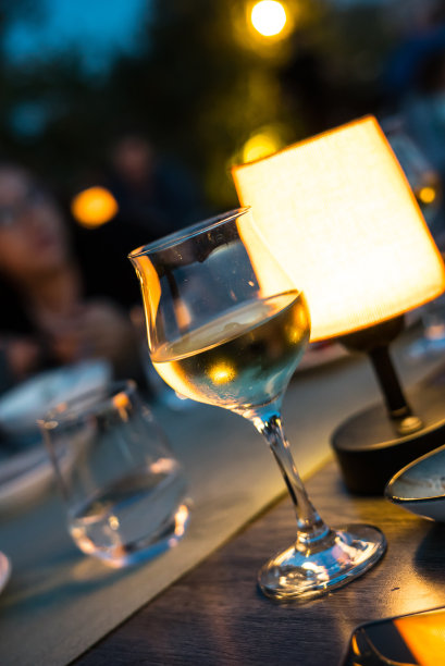 白葡萄酒是在晚上的杯子集中前景豪华氛围灯罩与bookh效果图片下载