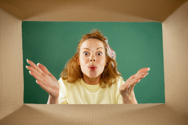 美丽的年轻女孩打开，打开纸箱盒子和看里面惊讶。情绪，黑色星期五，节假日，网上购物的概念图片下载