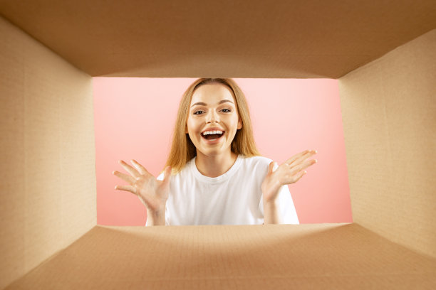 喜悦。美丽的年轻富有表现力的女孩打开，打开纸箱盒子，看里面。情绪，黑色星期五，节假日，网上购物的概念图片下载