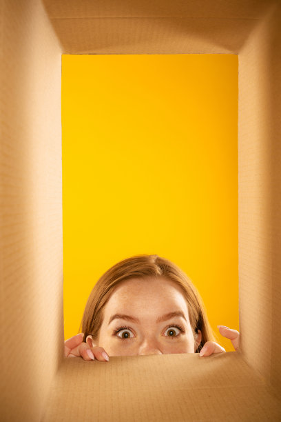 窥探盒子。迷人的女孩打开包装，打开纸箱，看里面的兴趣。黑色星期五，假日，网上购物的概念图片下载