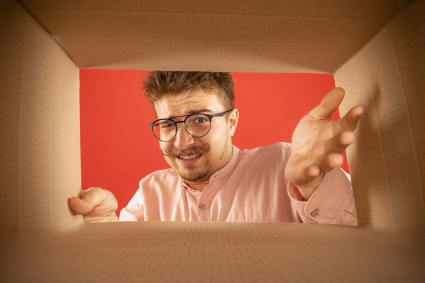 恼怒的男人打开包装，打开纸板箱看里面。传递，惊喜，礼物，负面情绪的概念。黑色星期五，节假日，网上购物图片下载