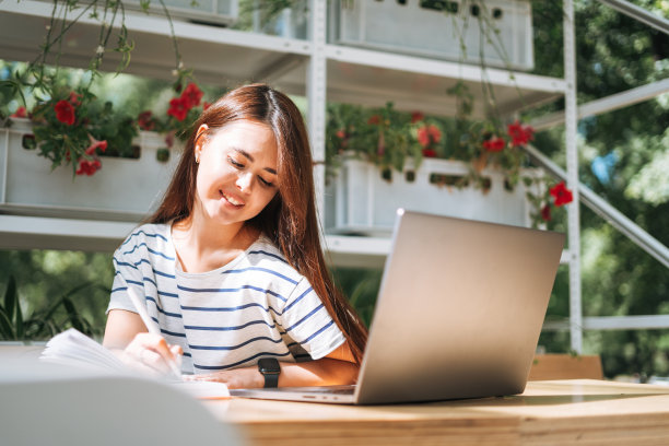 留着长发的年轻女学生自由职业者，在街头咖啡馆用笔记本电脑工作图片下载