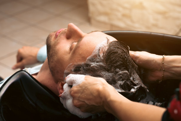 发廊师傅在理发店为客户洗头。男顾客接受理发师理发。护发、美容行业、理发理念图片下载