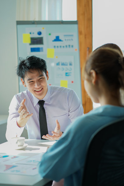 成功的亚洲男人、经理、商人与一名亚洲女同事在公司办公室的办公桌上工作，桌子上有一张财务图表和笔记本电脑。图片下载