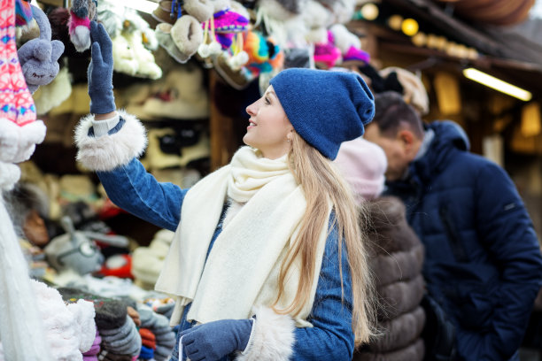 一个戴着蓝色帽子的女孩看着圣诞市场。圣诞节前雪天，买卖概念图片下载