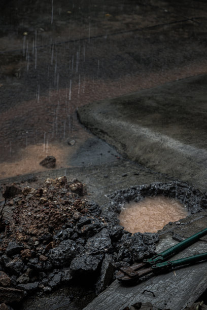 下雨时，我家门前漏水的水管破裂了。在旧混凝土和碎片上可以看到地上的洞和螺栓切割器。图片下载