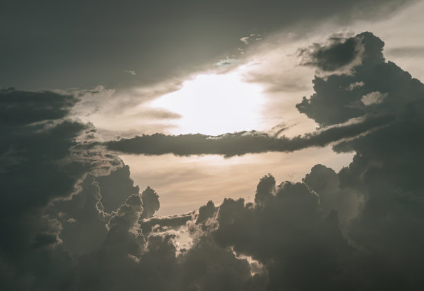 在傍晚的天空中，太阳透过云层，散发出引人注目的光芒。图片下载