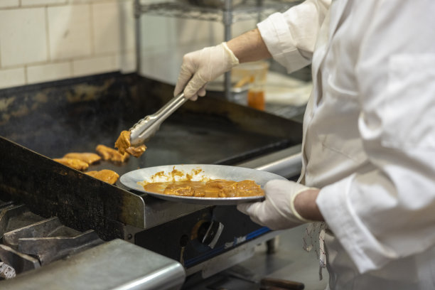 一个酋长，在餐厅的厨房里准备肉类，煎家禽。图片下载