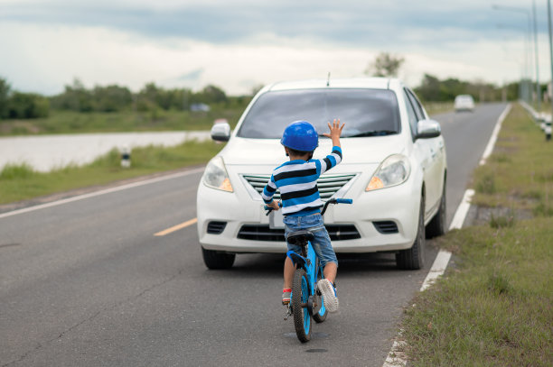 一个男孩在路上因自行车与汽车相撞而受伤。一个亚洲男孩被车撞了。道路事故的概念和减少事故从使用汽车在道路上。有选择性的重点。图片下载