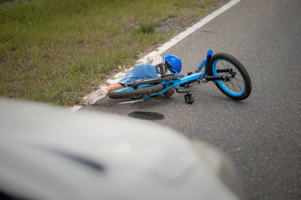 一个男孩在路上因自行车与汽车相撞而受伤。一个亚洲男孩被车撞了。道路事故的概念和减少事故从使用汽车在道路上。有选择性的重点。图片下载