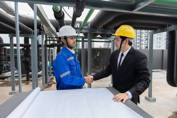 经理拜访在屋顶管架附近工作的工程师，检查进度图片下载