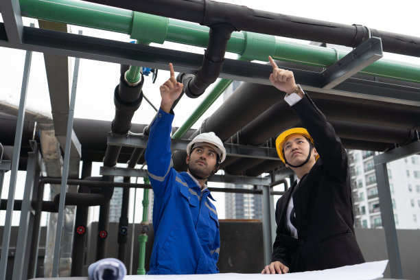 经理拜访在屋顶管架附近工作的工程师，检查进度图片下载