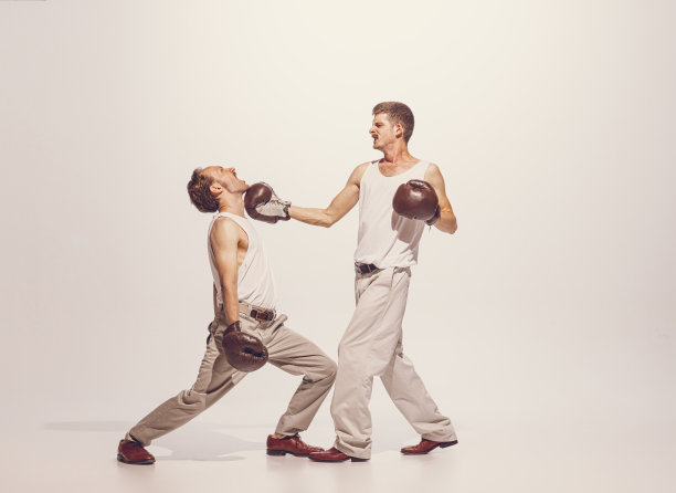 肖像的两个男人在玩，拳击手套孤立在灰色的工作室背景。与对手图片下载