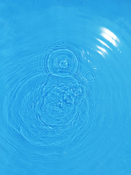 散焦模糊透明蓝色，清澈平静的水面纹理与飞溅和泡沫。时髦的抽象自然背景。阳光下的水波与复制空间。蓝色水彩灿烂。图片下载