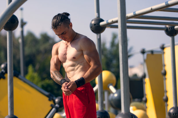 夏天的早晨，在公园的运动场上穿着红色短裤的英俊的年轻肌肉男。运动、健身、健康的生活方式理念图片下载