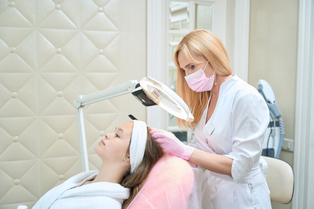 美容师检查女孩的头，透过放大镜灯看图片下载