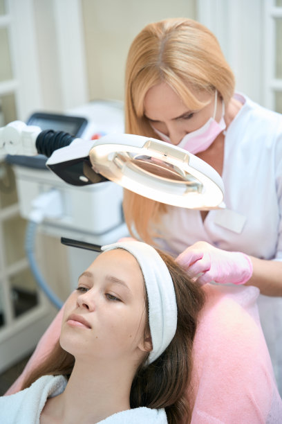 美容师将放大镜灯置于病人头上图片下载