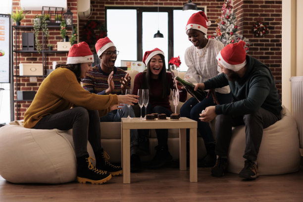 圣诞派对上，快乐的同事往玻璃杯里倒酒图片下载