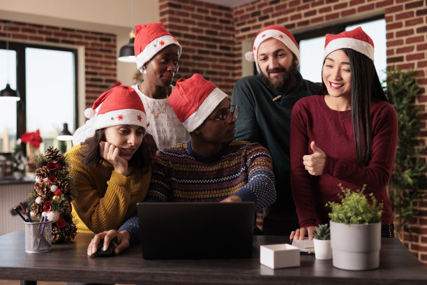在节日的办公室里使用笔记本电脑的多民族团队图片下载