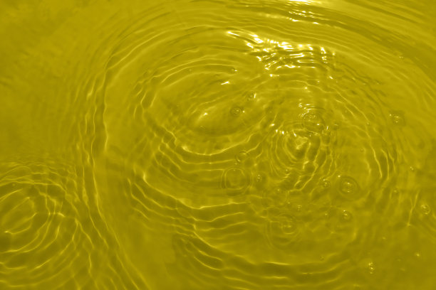 散焦模糊透明，黄色，清澈平静的水面纹理与飞溅和泡沫。时髦的抽象自然背景。阳光下的水波与复制空间。黄色的水彩闪亮。图片下载