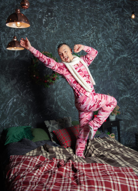 快乐，有趣，快乐的男人穿着睡衣在床上跳舞在圣诞节的时间图片下载