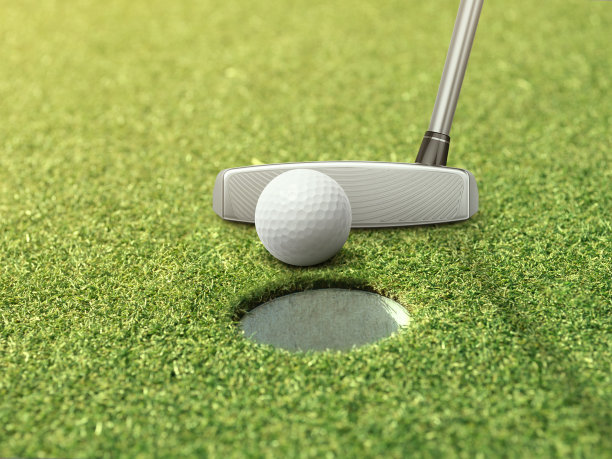 高尔夫球和推杆在高尔夫球洞旁边的草地上图片下载