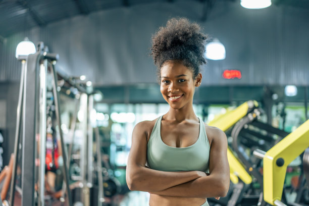 非洲运动女孩穿着运动服在健身俱乐部锻炼的肖像。有魅力的年轻运动员在健身房或健身俱乐部用器械完成训练后交叉站立。图片下载