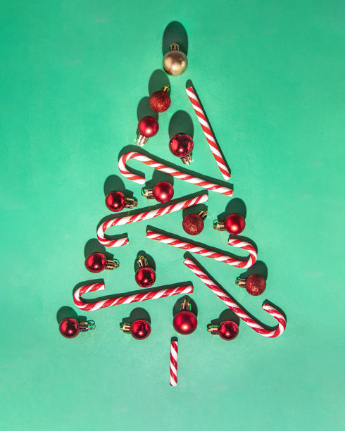 圣诞树的传统。圣诞节传统的拐杖糖和绿色背景的红色小玩意儿。极简新年概念。糖棒装饰平铺。图片下载