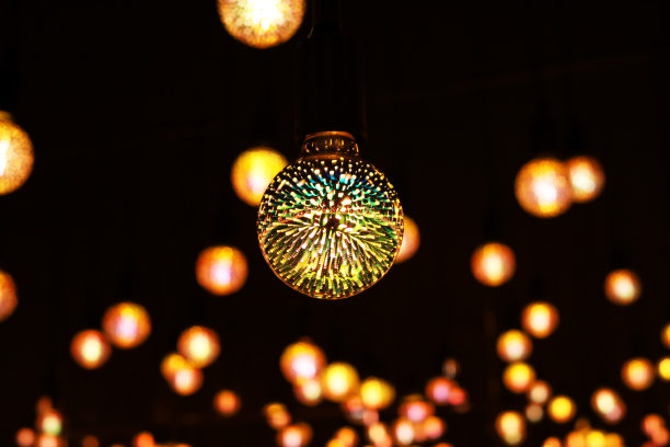 装有彩色灯泡的灯泡在黑暗中发光。在黑暗中发光的彩色图案灯泡。有选择性的重点图片下载