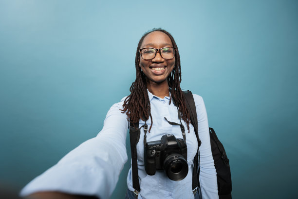 欢快微笑的青年摄影师与单反相机自拍照片图片下载