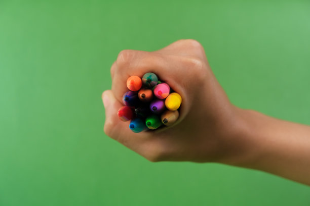 在绿色背景上手持彩色标记的人的手图片下载