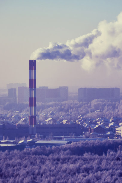 冬天的城市，工厂烟囱冒着烟，房子被雪覆盖图片下载
