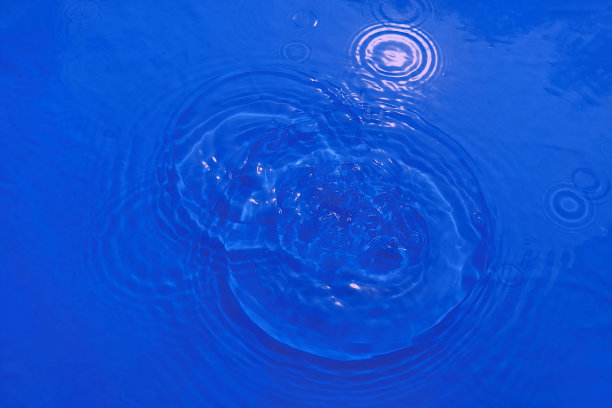 散焦模糊透明蓝色，清澈平静的水面纹理与飞溅和泡沫。时髦的抽象自然背景。阳光下的水波与复制空间。蓝色水彩灿烂。图片下载