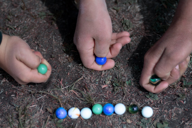 孩子们在街上玩弹珠。乡村场景中的大理石特写。图片下载