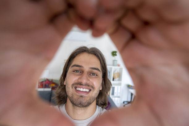 英俊的年轻人一边自拍一边做心形图片下载