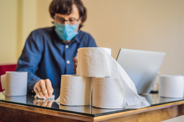 冠状病毒戴着防护口罩在家工作的男子。隔离戴防护口罩的冠状病毒。在家工作。用消毒凝胶清洗。买了很多卫生纸图片下载