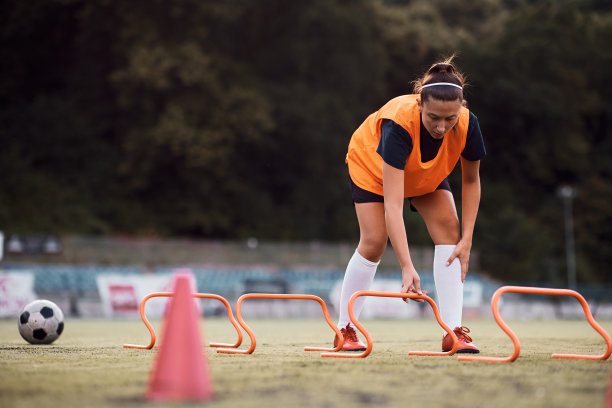 女子足球运动员在运动场上设置运动训练器材。图片下载