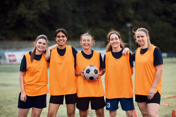幸福的女子足球队在体育场看着镜头的肖像。图片下载