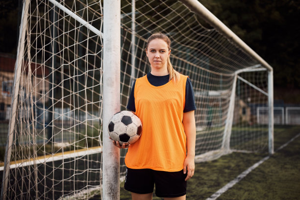 运动妇女的肖像与一个球在足球训练看相机。图片下载