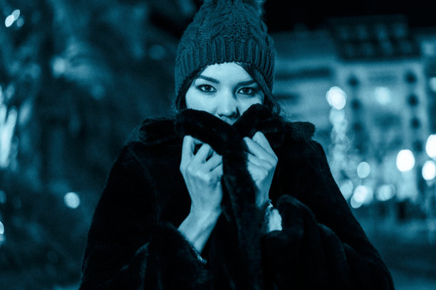 圣诞在城市，冬天在装饰。在圣诞节寒冷的冬夜戴上帽子和围巾图片下载