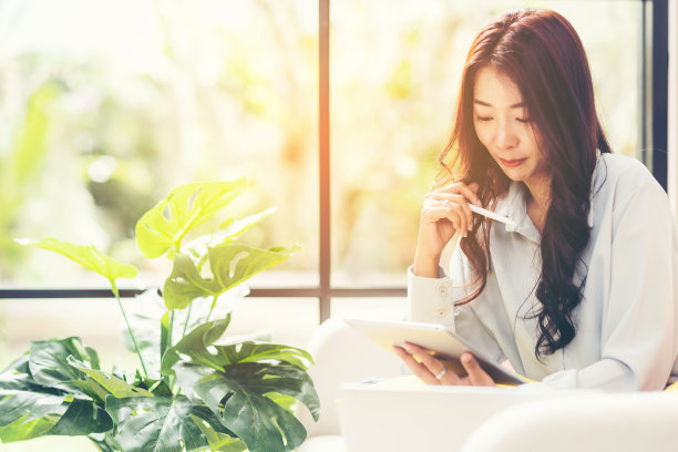 快乐的年轻女性在家在线工作和开会。生活方式自由，在客厅喝咖啡放松和冷静，自然花园背景。生活方式的概念图片下载