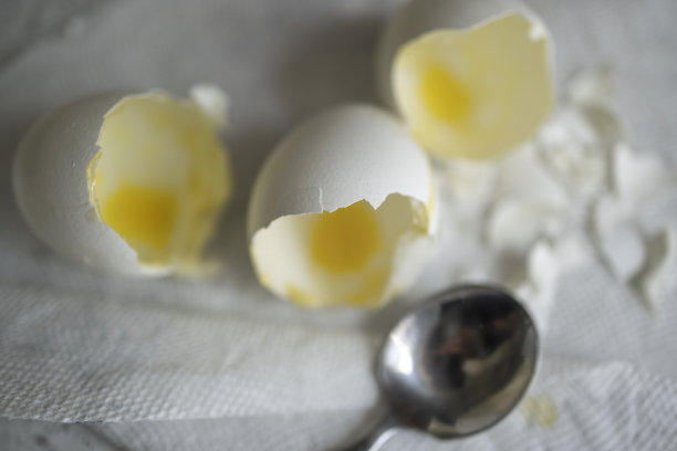 用勺子在厨房桌子上敲碎的鸡蛋。图片下载