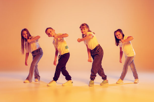 一群穿着休闲服装的孩子在舞蹈课上跳舞，在霓虹灯滤光下的黄色背景下。艺术、音乐、时尚图片下载