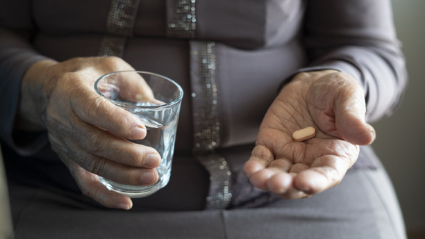 老妇人拿着药片和一杯水图片下载